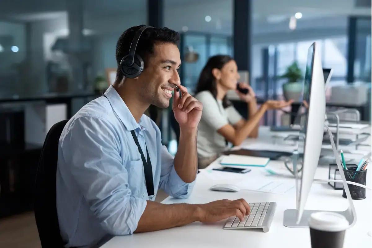 IT support technician on a call while working at a computer in an office