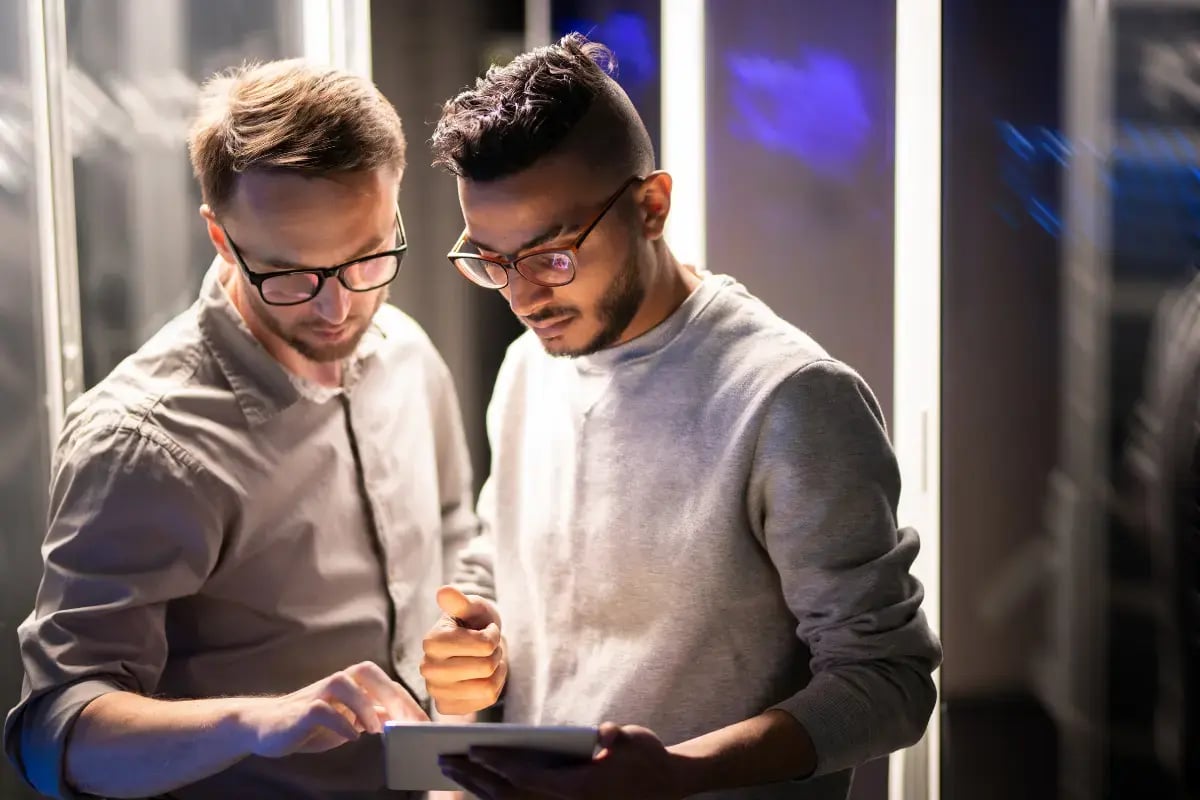 Two IT professionals working on a tablet in a server room for on-site support